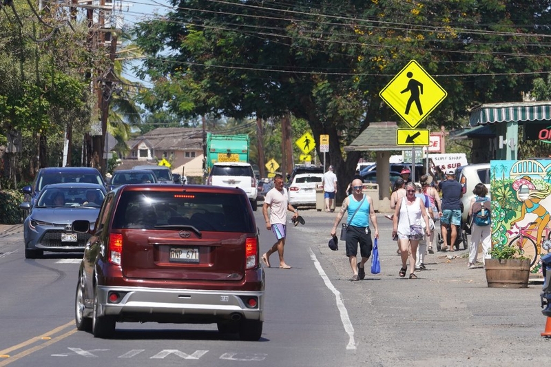 Pedestrians walk along Kamehameha Highway in Haleiwa town.