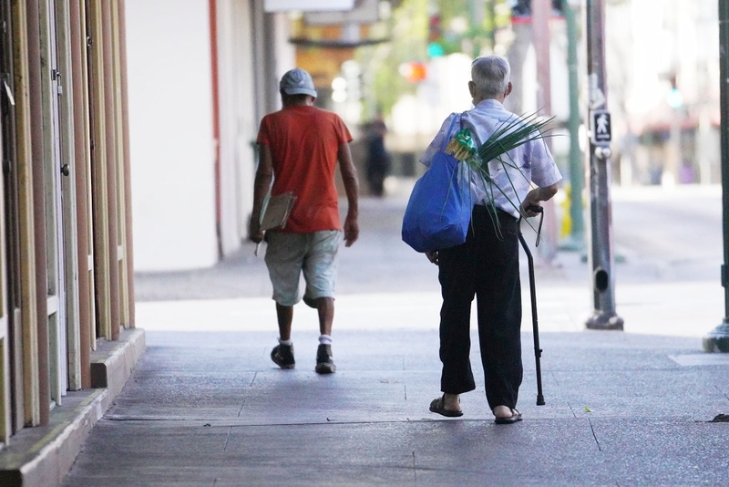 Elderly man walks with cane along Hotel Street in metropolitan Honolulu.