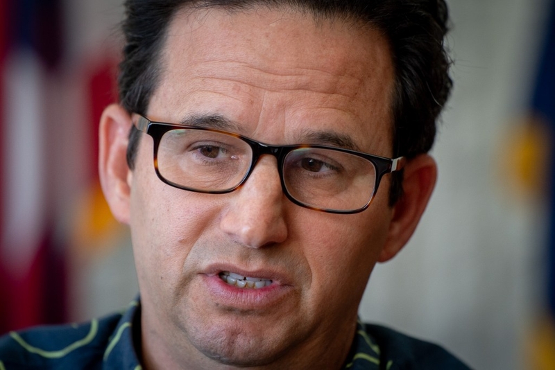 A tightly framed photo of a clean-shaven dark-haired man wearing glasses.