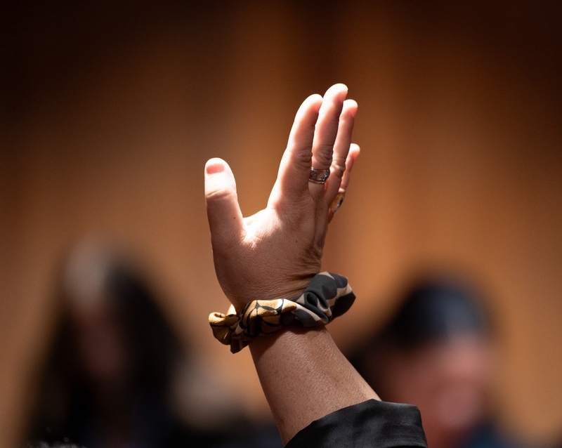 A call for attention to the student delegates to 'Aha 'Ōpio at the Capitol June 22, 2026. The hand belongs to Brittney Kamele Kapaona, a delegate in 1991, who guided current students. (Craig Fujii/Civil Beat/2026)