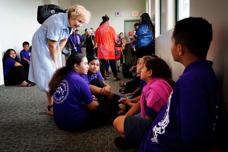 St. John’s Episcopal Church’s Kahu Kerry Joffrion talks story with Kula Aupuni Niihau A Kahelelani Aloha students she teaches outside of the school and in the church choir Wednesday, July 22, 2026, in Līhuʻe. She and St. John’s attended to support the keiki. One of the few schools dedicated to teaching the Niʻihau dialect of the Hawaiian language is at risk of losing its campus with the school year just a few weeks away. (Kevin Fujii/Civil Beat/2026)