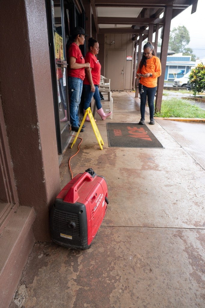 Ua Viernes, left, Malia Woods, center, and Margarita Emilyon wait for customers at their hardware store in Haleʻiwa after Lala passed south of Oʻahu August 16, 2026. They used a generator for some power.  (Craig Fujii/Civil Beat/2026)