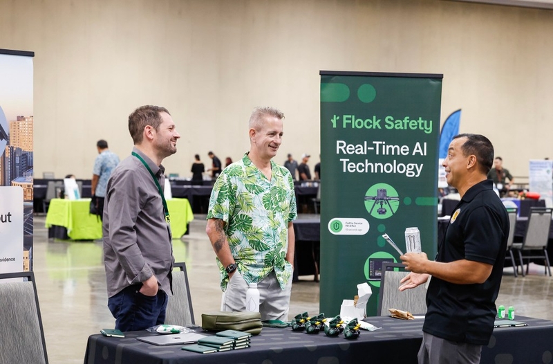 Flock Safety representatives Ben Shank, left, and Louis Wershaw talk with DLE chief special investigator Mike Lambert, right, during the Dept. of Law Enforcement’s Public Safety Expo, Saturday, Sept. 26, 2026, at the Hawaiʻi Convention Center in Honolulu.  (Jamm Aquino/Civil Beat/2026)