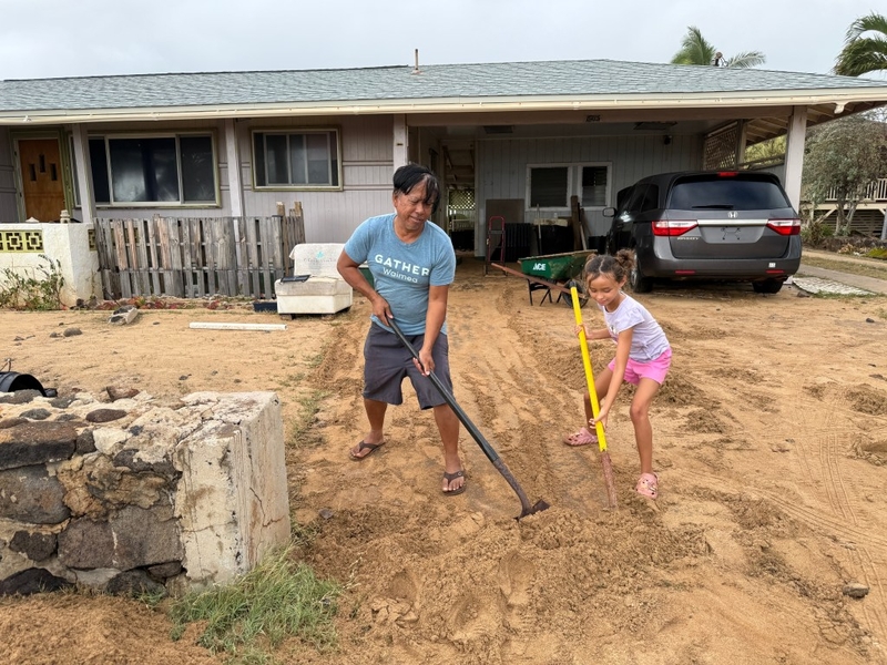 Darren Carillo and his niece shovel sand out of his driveway across from the beach in Kekaha. (Noelle Fujii-Oride/Civil Beat/2026)