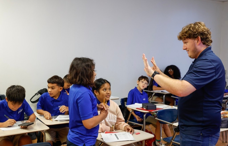 Sixth-grade math teacher Byron Bass, right, assists students Hope Singeuo, middle, and Angelica Meikei,front,  with a math problem at Kūlia Academy, Wednesday, Sept. 30, 2026, in Kalihi.  Kūlia Academy’s middle school math achievement has had unprecedented improvement, and had the highest middle school math scores in the state last year. (Jamm Aquino/Civil Beat/2026)