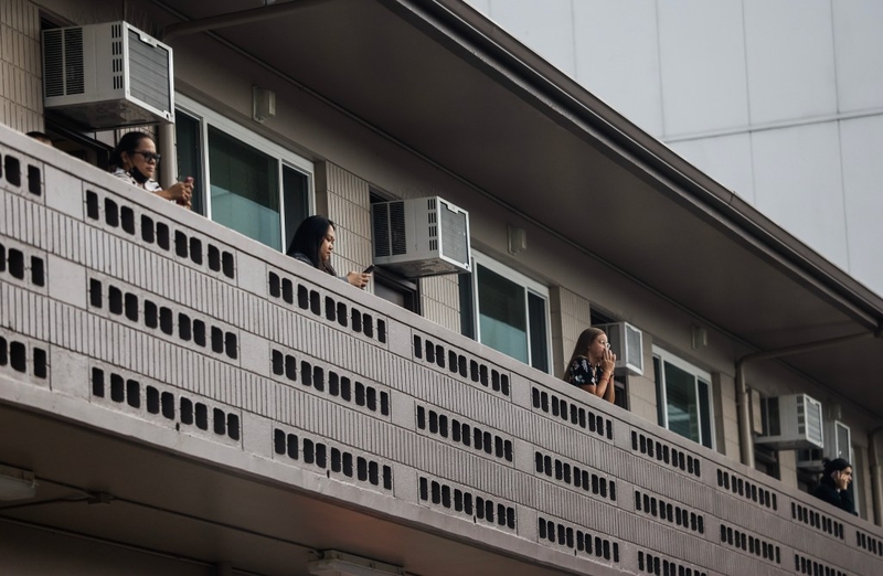 Occupants of an office unit at 1513 Young Street enjoy some fresh air as window air-conditioning units are seen in the background, Monday, Oct. 26, 2026, in Honolulu. (Jamm Aquino/Civil Beat/2026)