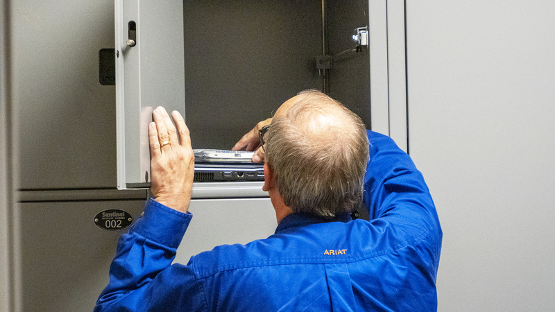 A Marion County undersheriff on Aug. 16, 2023, reaches into an evidence locker for items seized from the Marion County Record during an Aug. 11, 2023, raid by city police.