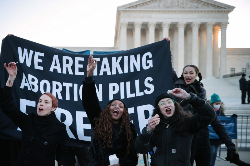 Lila Bonow, Alana Edmondson and Aiyana Knauer prepare to take abortion pill while demonstrating in front of the U.S. Supreme Court on Dec. 1, 2021, in Washington, D.C.