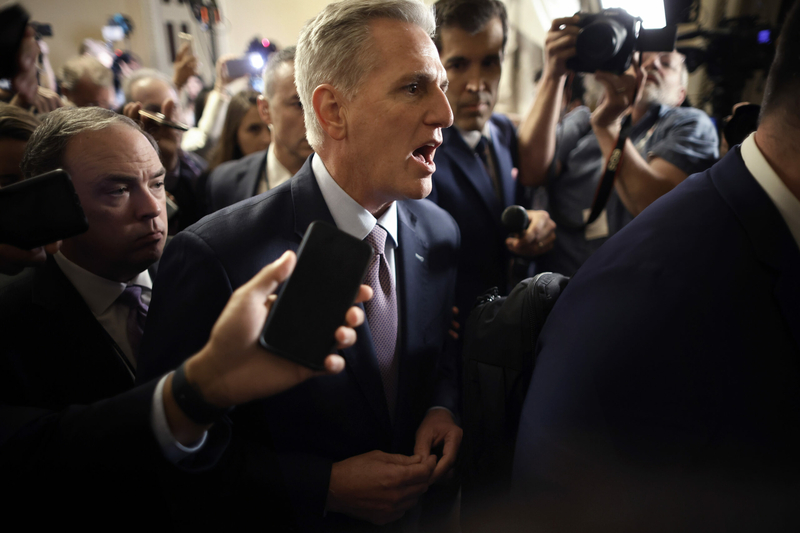 Former Speaker of the House Kevin McCarthy is surrounded by staff, security and journalists as he walks to the House chamber ahead of a vote in which he would be removed from his post.