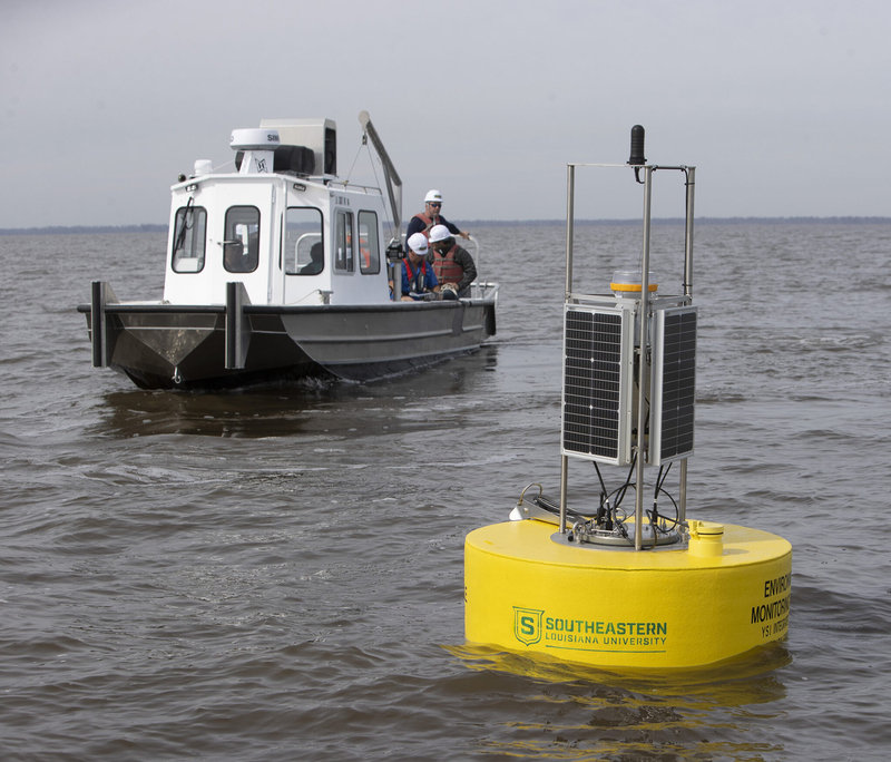 Yellow buoy floats in lake with boat in background
