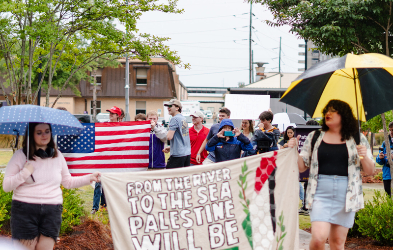a group of protesters hold flags and protest signs