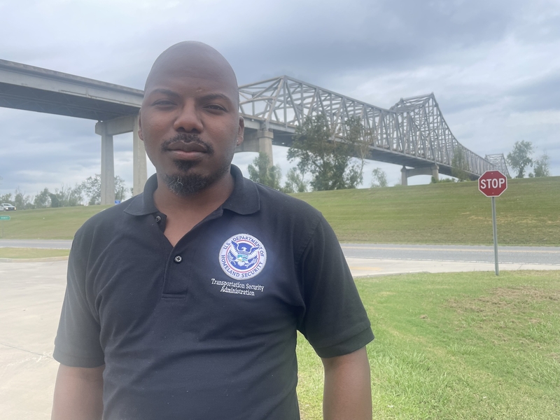 Chad Roussell, a West St. John resident, is pictured with the Gramercy Bridge and Mississippi River levee in the background. (Greg LaRose/Louisiana Illuminator)