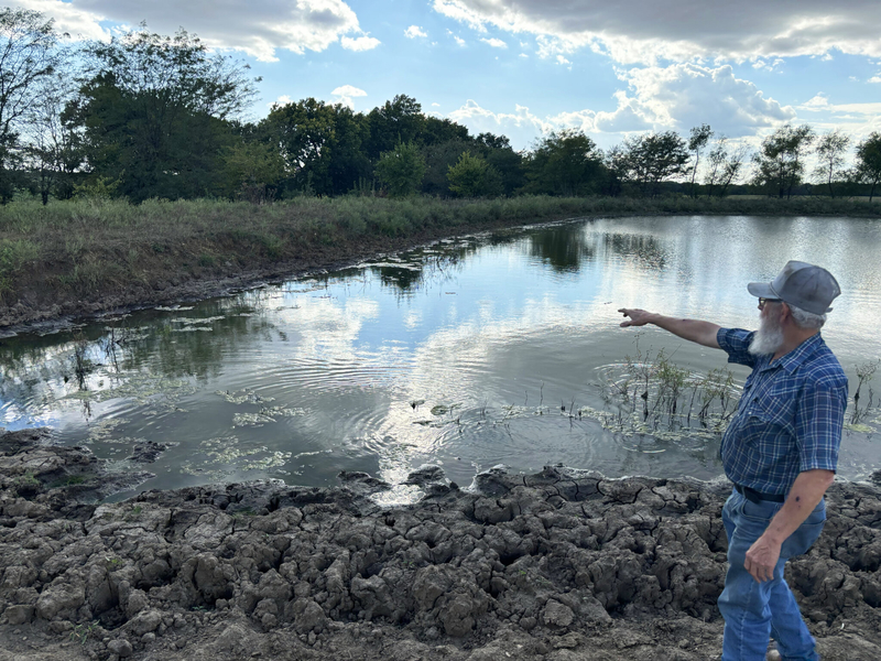 Wilburn Harris pointed at the low water level of a pond on his farm in Drexel, Missouri