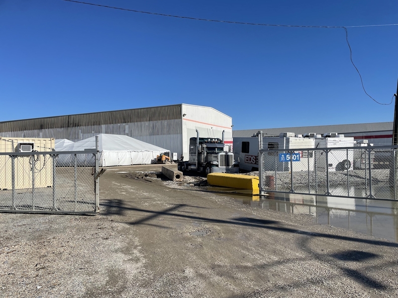 A muddy driveway leads to a warehouse on France Road in New Orleans that is being used as a temporary shelter for the unhoused.