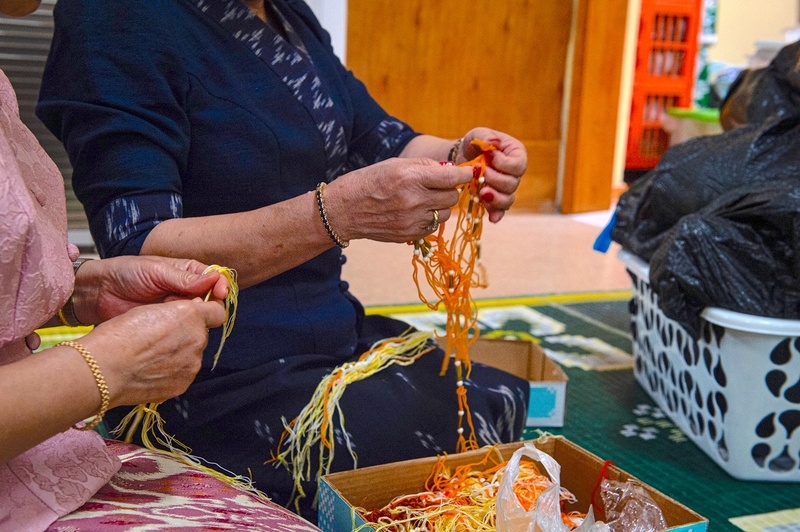 Women's hands are shown making decorative string for the Sou Khan ceremony.