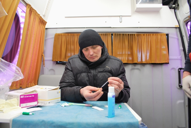 Mykolai, an addict who declined to provide his last name, pricks is finger to test himself for HIV and hepatitis while seated at a table inside a van that serves as a mobile clinic in Kyiv, Ukraine.