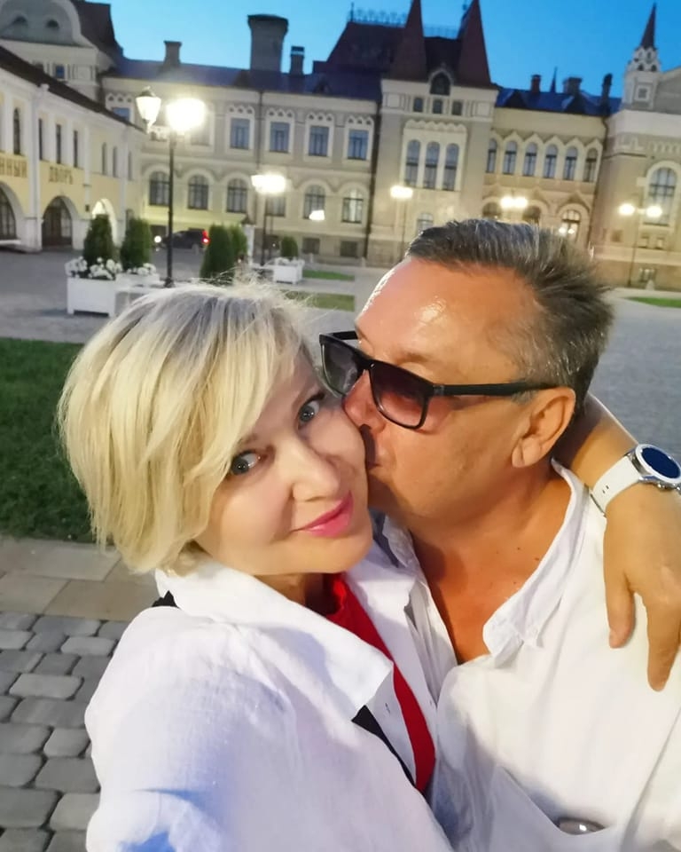 Alexey Demin kisses the cheek of his wife, Svetlana, as she takes their picture with her phone.