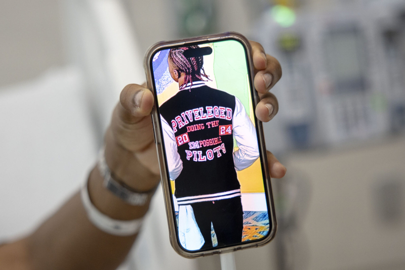 Daniel Cressy shares an photo of himself on his phone that shows him wearing a jacket from his brand “Privileged Pilot” while he begins gene therapy treatment at Manning Family Children's Hospital in New Orleans