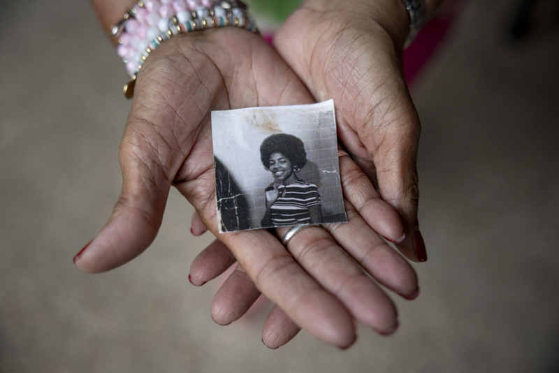 Former teacher Grace Lomba holds a photograph of herself as a young teacher at Alfred Lawless High School in the early 1970s