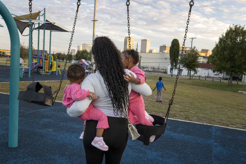 Mariah Lee carries her daughters in her arms at the Lafitte Greenway playground in New Orleans