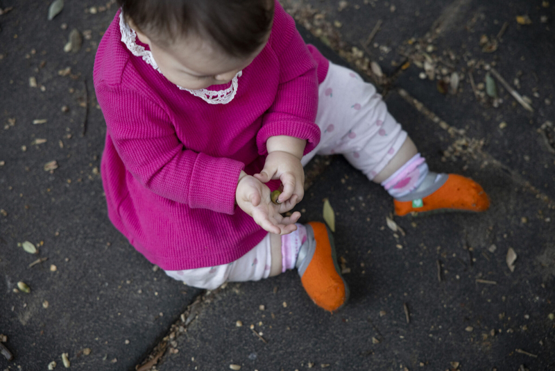 Edith Salmon, 10 months, plays with dirt and other debris scattered across the playground’s rubber tiles at Mickey Markey Park