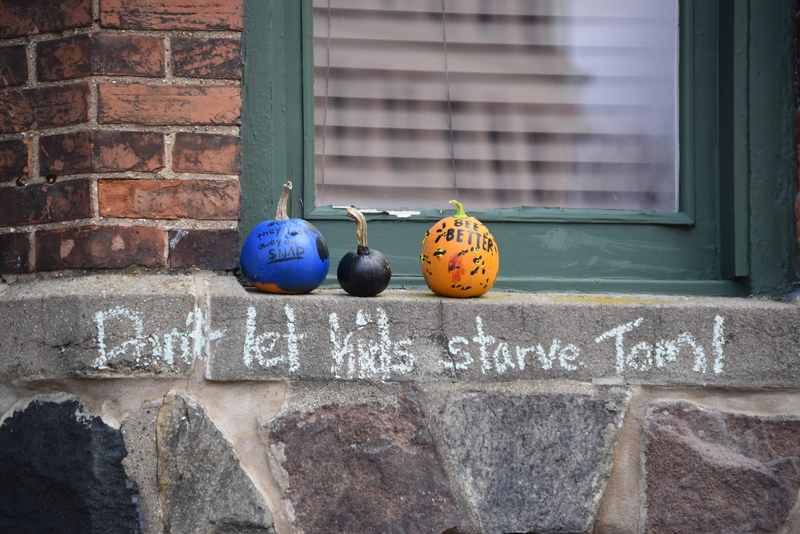 Pumpkins sit on a window ledge above chalk that reads "Don't let kids starve Tom!"