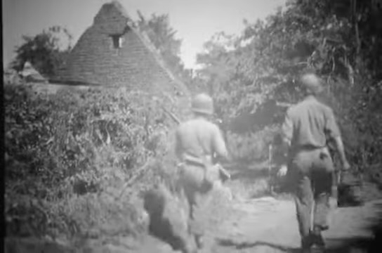 Two soldiers from the 28th Division walk amid the ruins of Gathemo, France, in August 1944. (Screenshot of National Archives film)