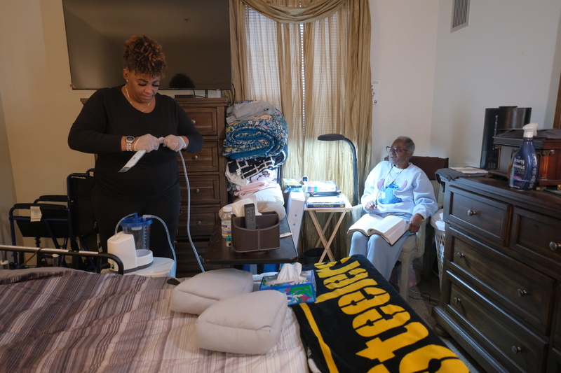 Home care worker Angela Engram tends to her client Linda Stokes’ bedside medical equipment. (Photo by Jeff Ricker for Capital &amp; Main)
