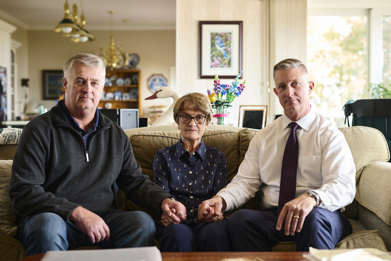 A severe pressure wound made it painful for Paul Webb Jr. to stand or sit. His wife, Judy, and sons Darel (left) and Paul III cared for him at home during the weeks before he died. (Dustin Franz for KFF Health News) Photo shows Webb's two sons sitting with their mother.