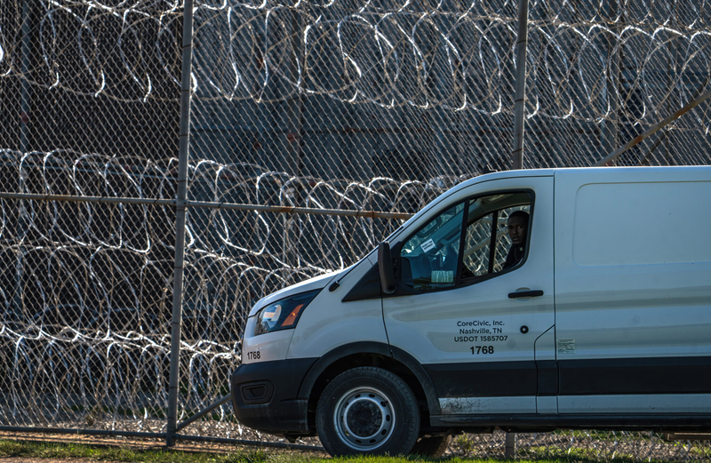 A van is parked next to rows of wire outside a prison.
